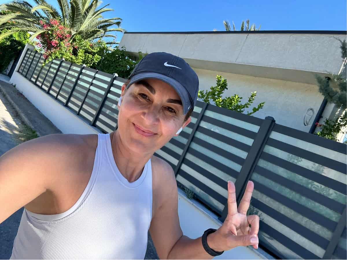 Onward team member smiling outdoors while wearing earbuds and holding up a peace sign.