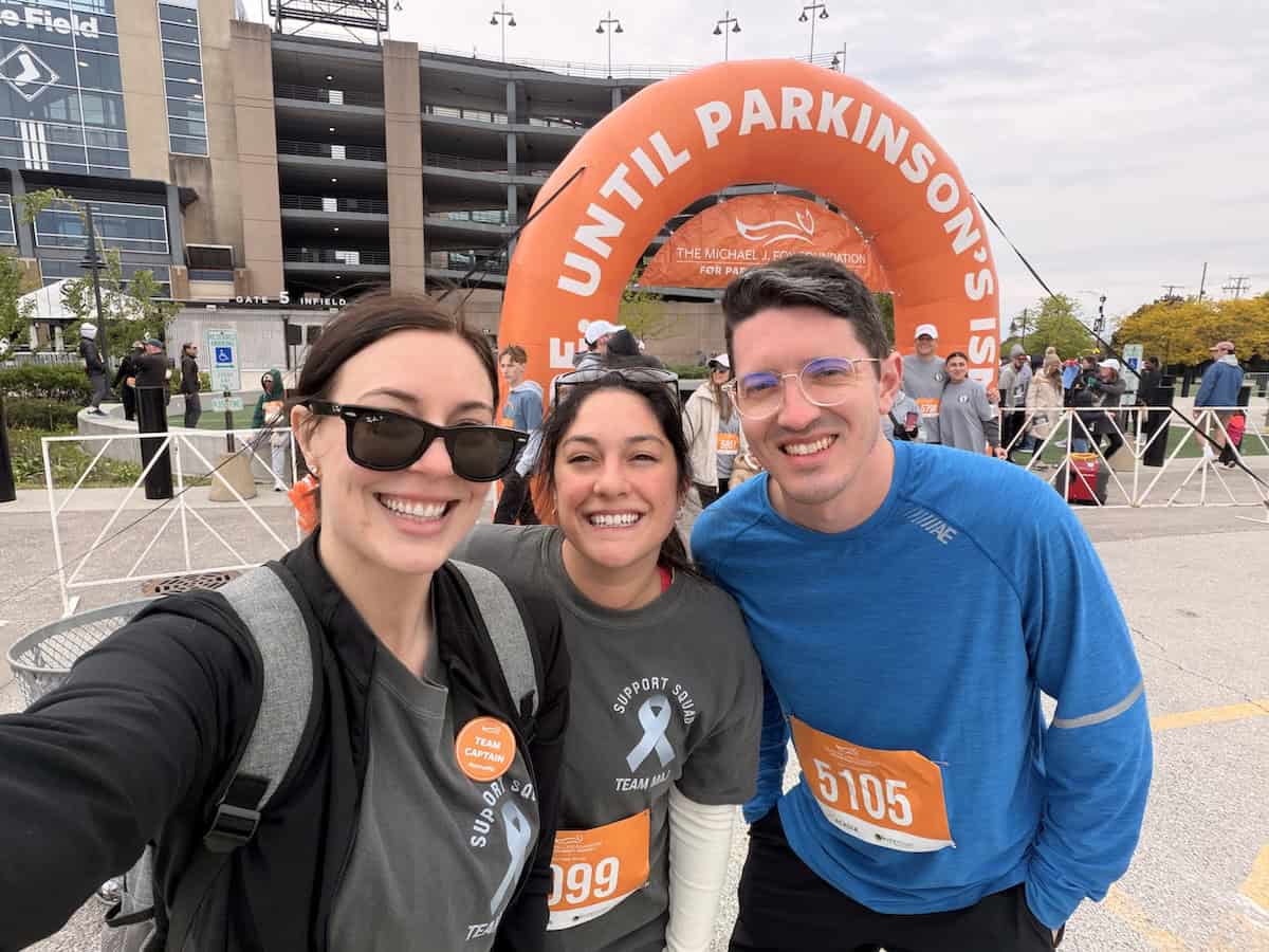 Three smiling team members at a community walk event supporting inclusion and awareness.