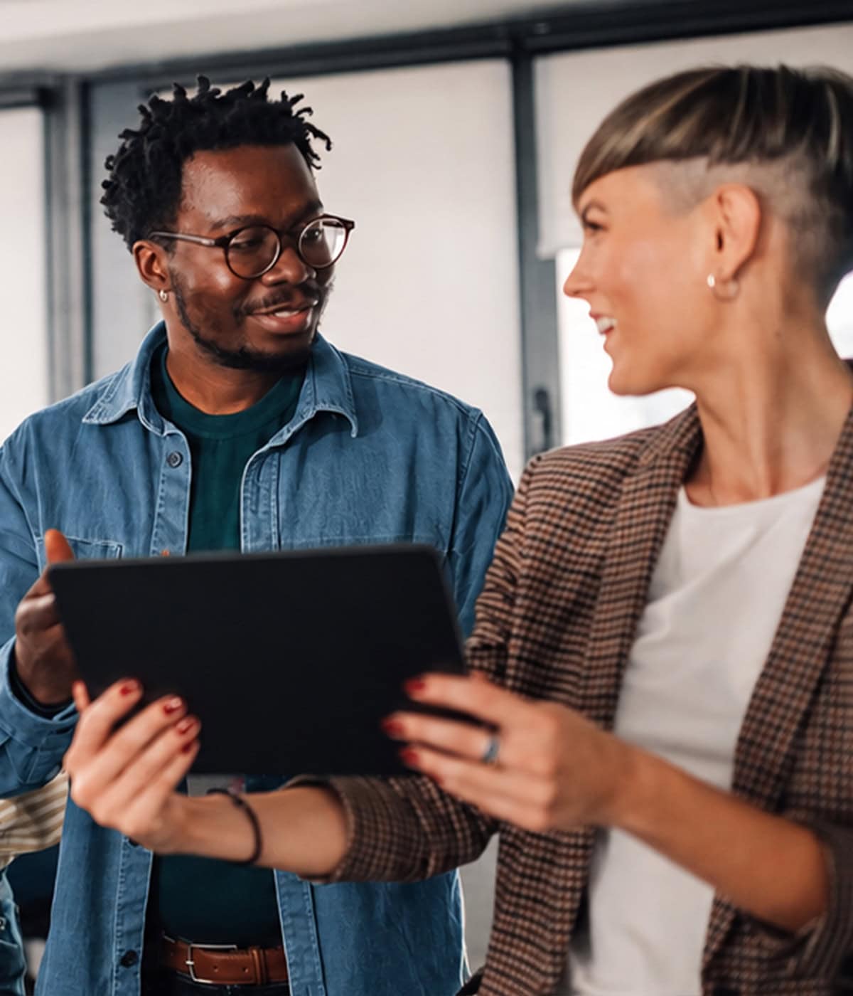 Two professionals collaborating around a tablet in a modern office, representing Onward Search talent solutions.